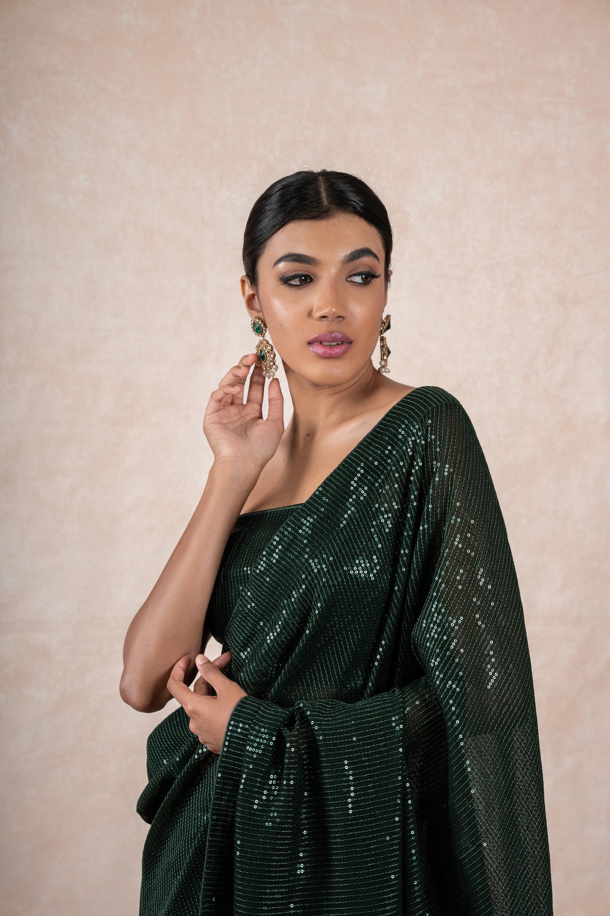 A model of Le Pleat draped in a sequin georgette designer saree with matching green sequin blouse material.