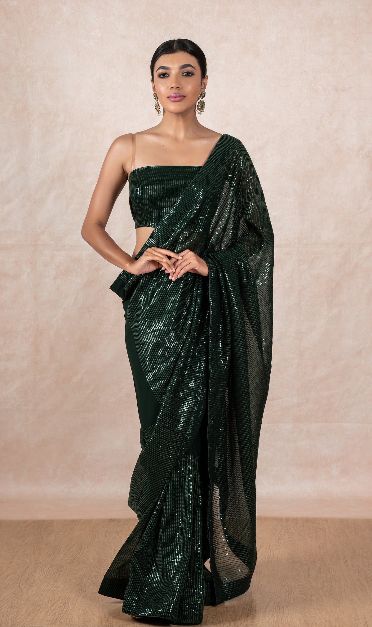 A model of Le Pleat draped in a sequin georgette designer saree with matching green sequin blouse material.