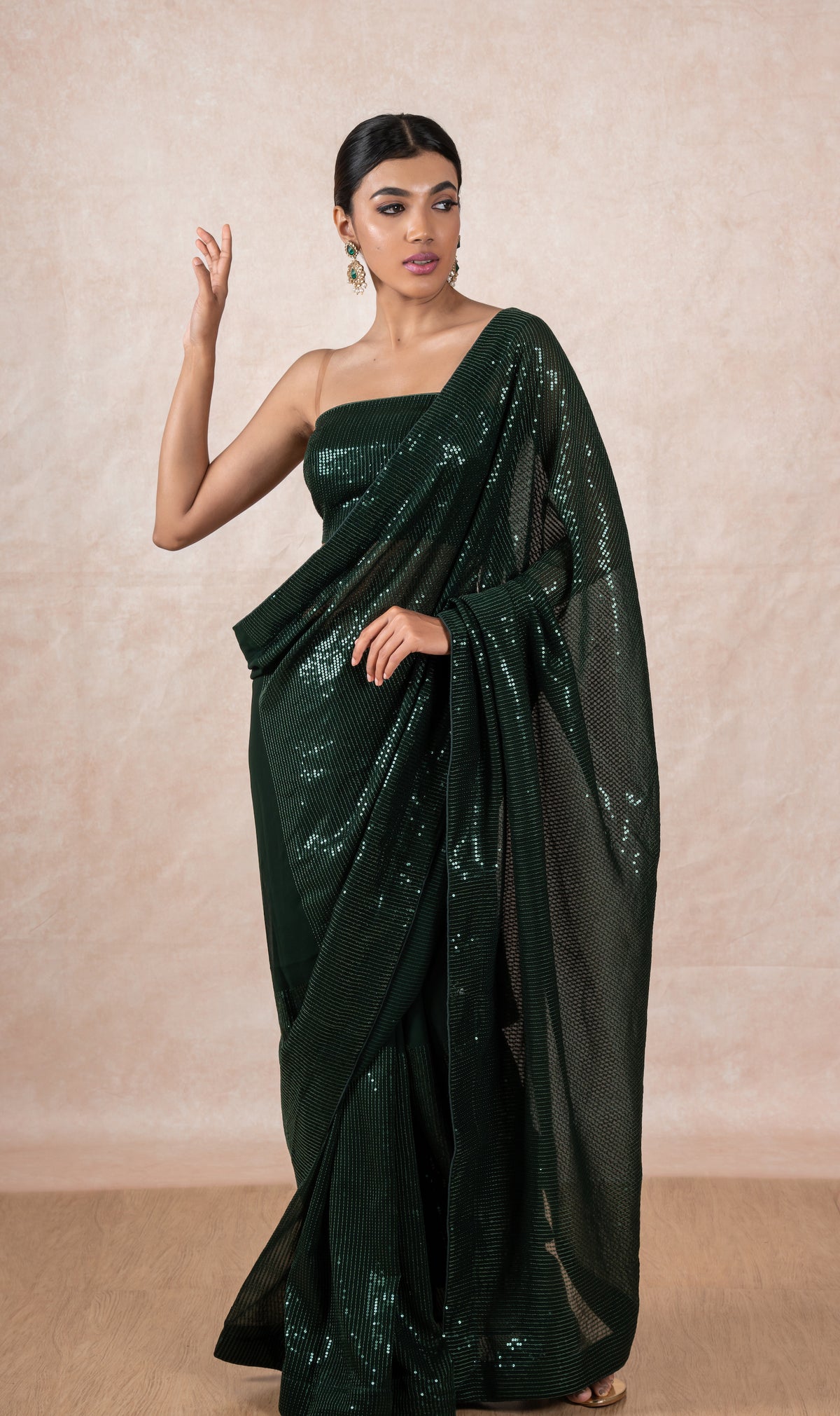 A model of Le Pleat draped in a sequin georgette designer saree with matching green sequin blouse material.