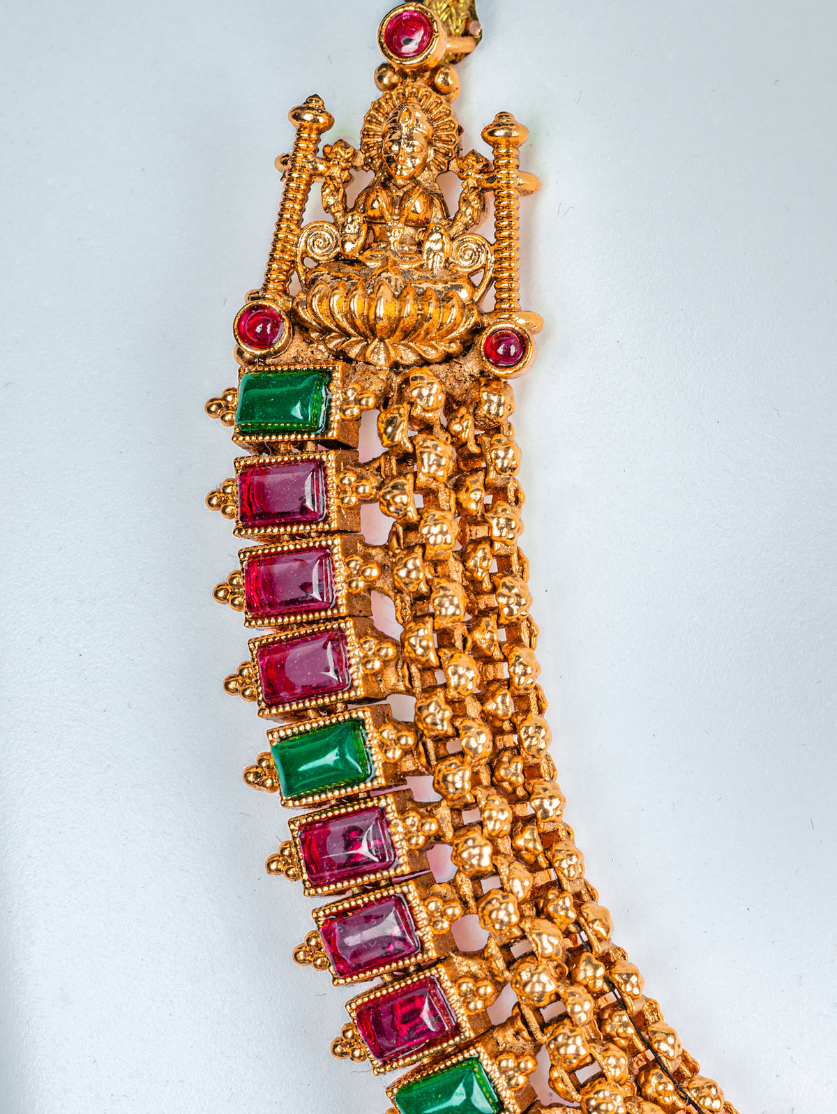 A traditional gols color choker set with lakshmi goddess, red and green kundan stone and jhumkas