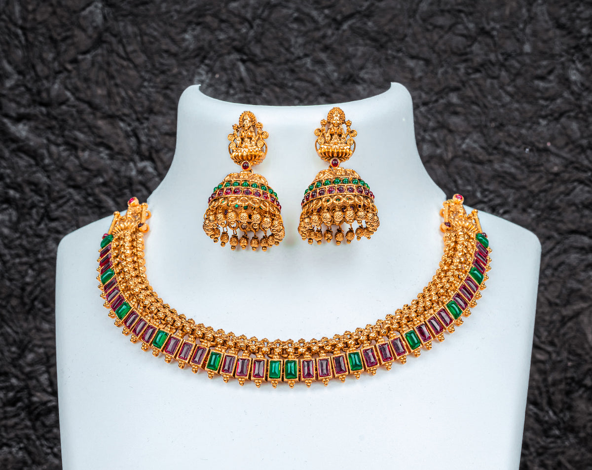 A traditional gols color choker set with lakshmi goddess, red and green kundan stone and jhumkas