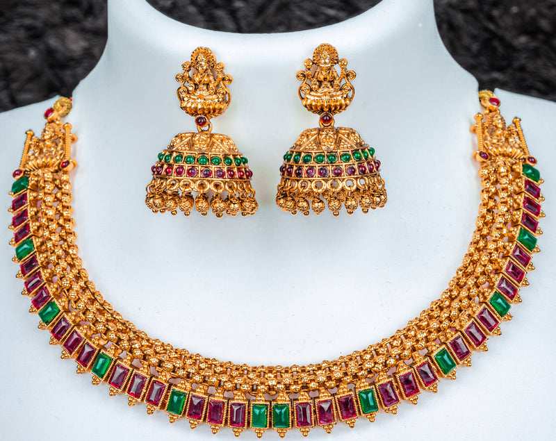 A traditional gols color choker set with lakshmi goddess, red and green kundan stone and jhumkas