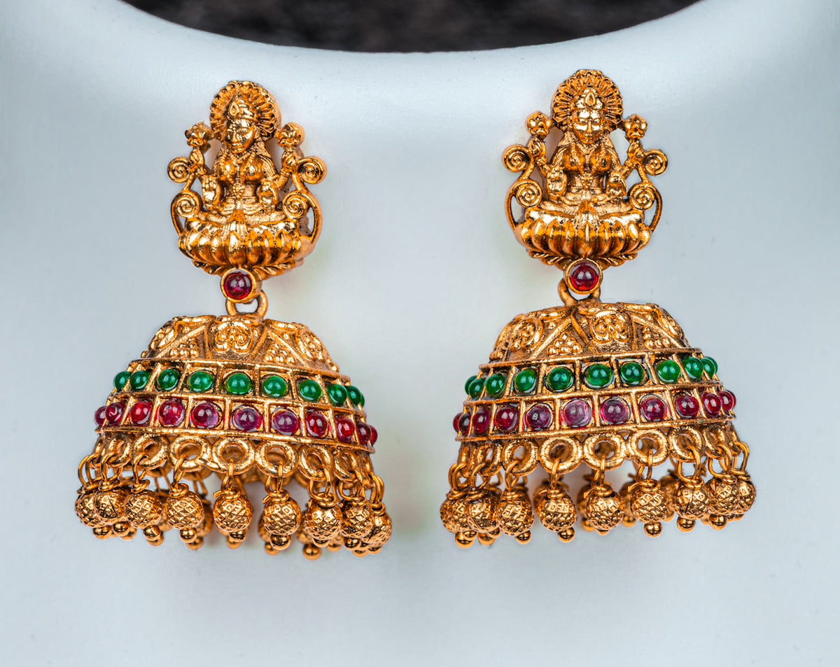 A traditional gols color choker set with lakshmi goddess, red and green kundan stone and jhumkas