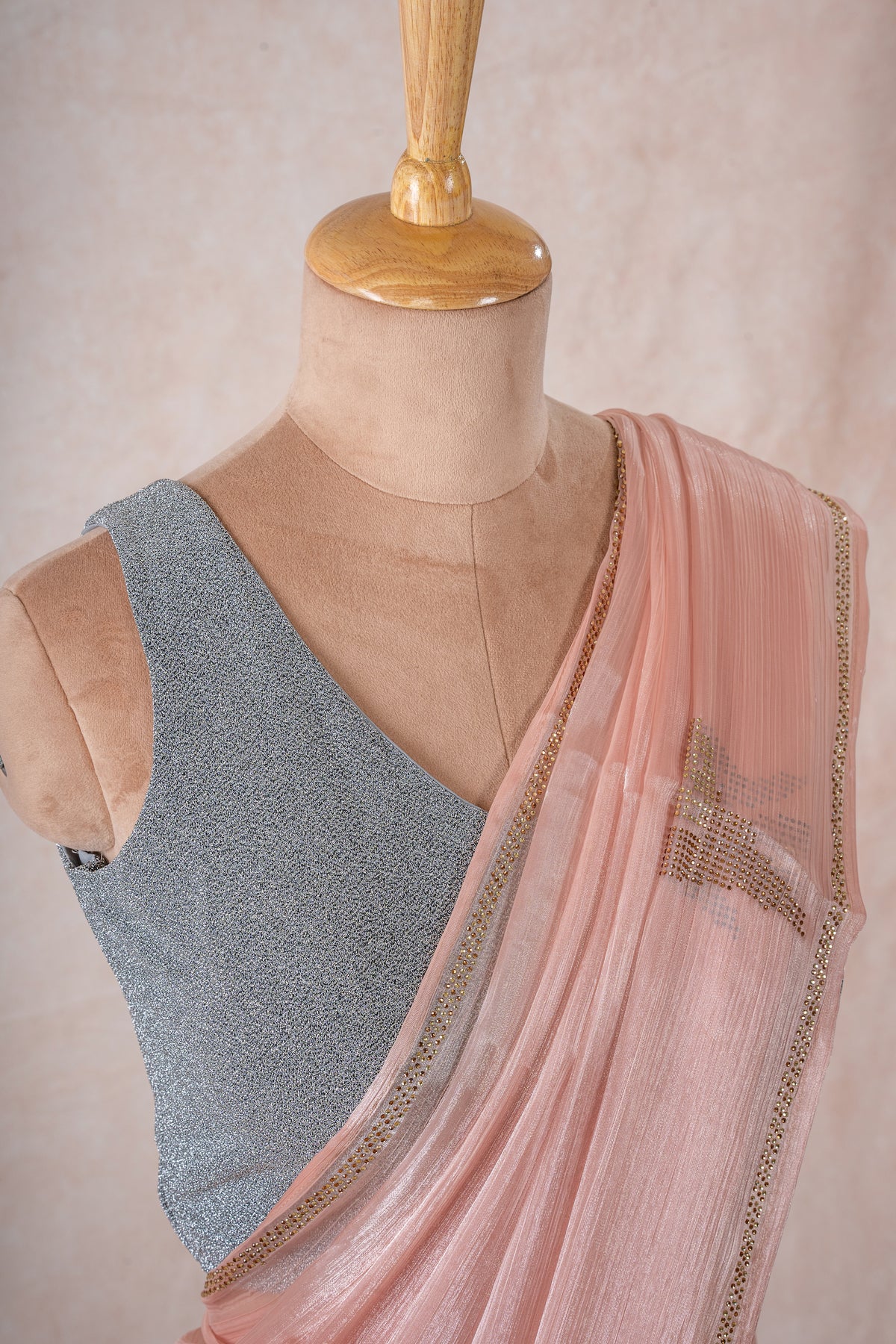 A mannequin draped in a sheer lightweight pink chinon chiffon saree with imitation swarovski stone crystal embellishments, sleeveess grey glitter blouse and pink blush saree shaper