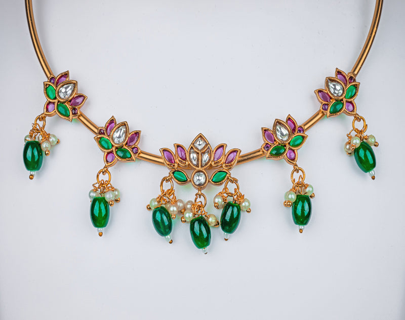 A gold pipe choker necklace with lotus design, pink stone and green beads, earrings in lotus design