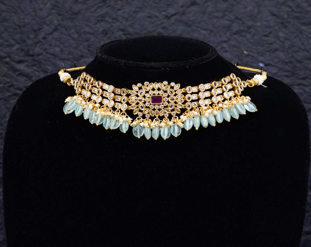 A fancy choker set with earrings desiged with blue beads and white kundan stones