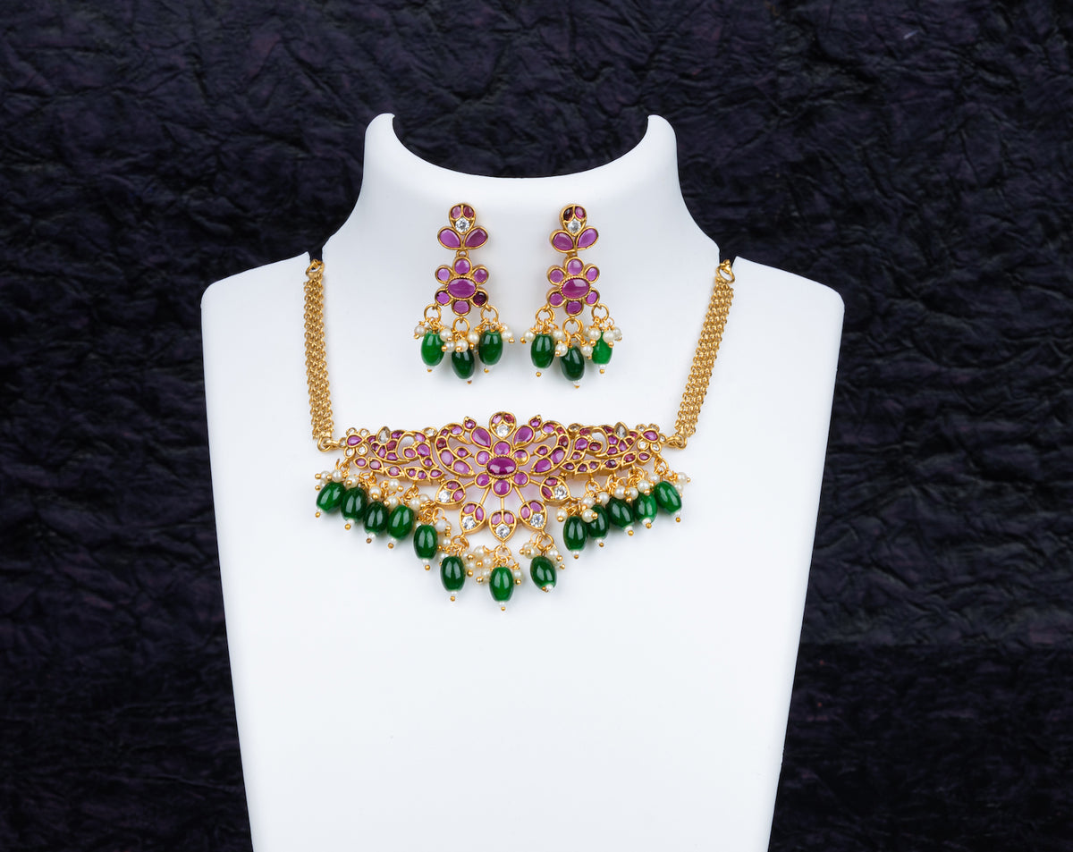 An elegant necklace set in peacock design with pink kundan stone and green beads, and matching earrings