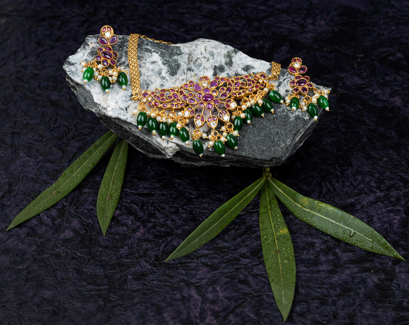 An elegant necklace set in peacock design with pink kundan stone and green beads, and matching earrings