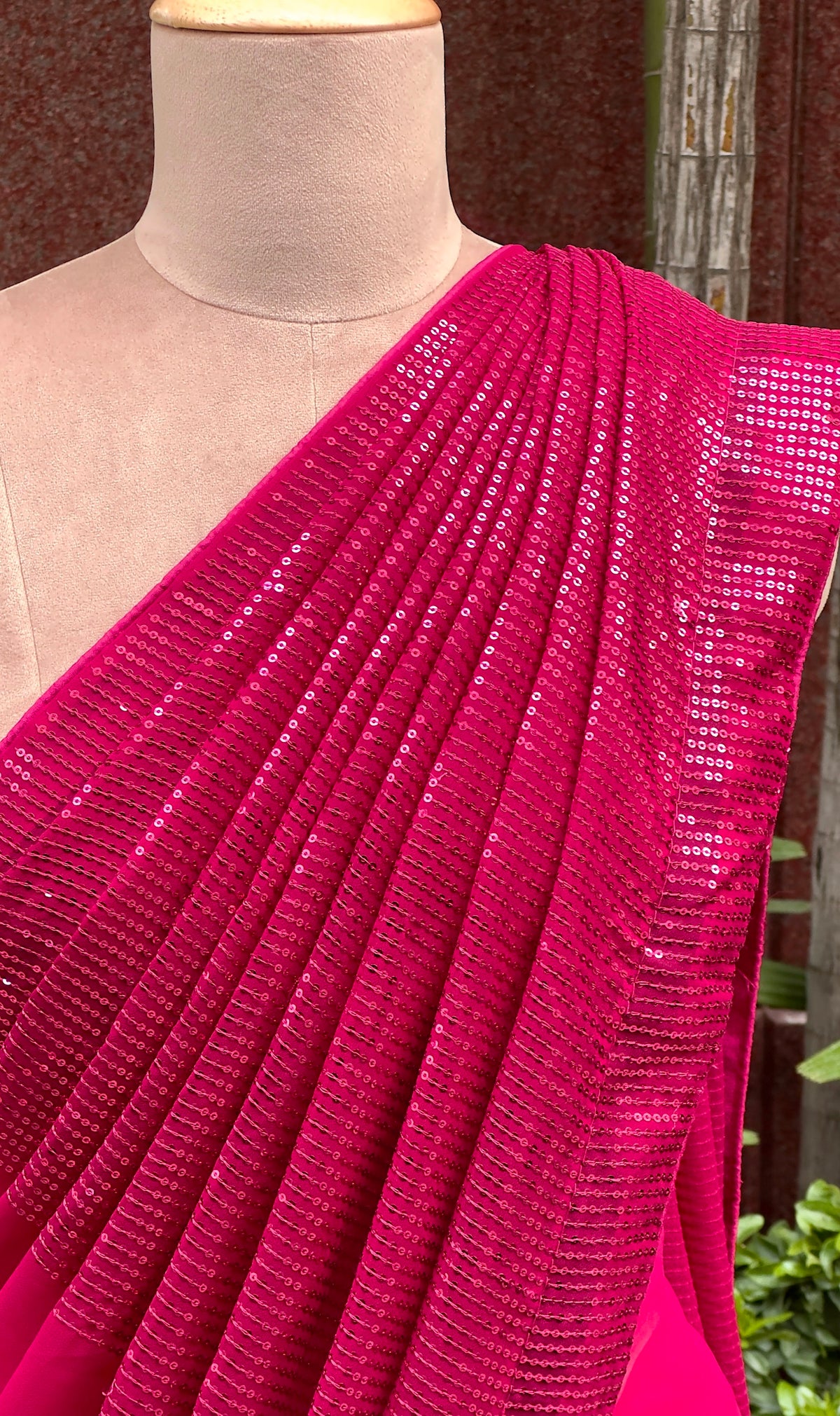 A mannequin draped in a rich pink designer saree embellished with pink sequin embroidery