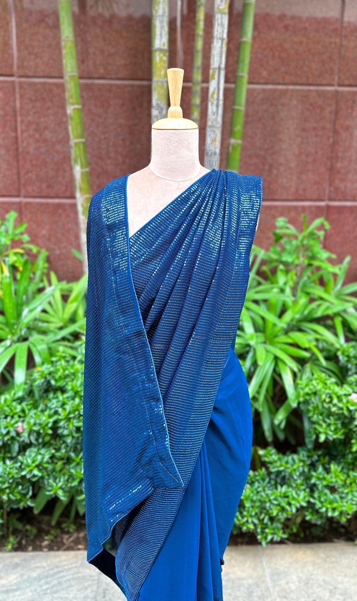 A mannequin draped in a stunning blue sequin saree embellished with blue sequin works