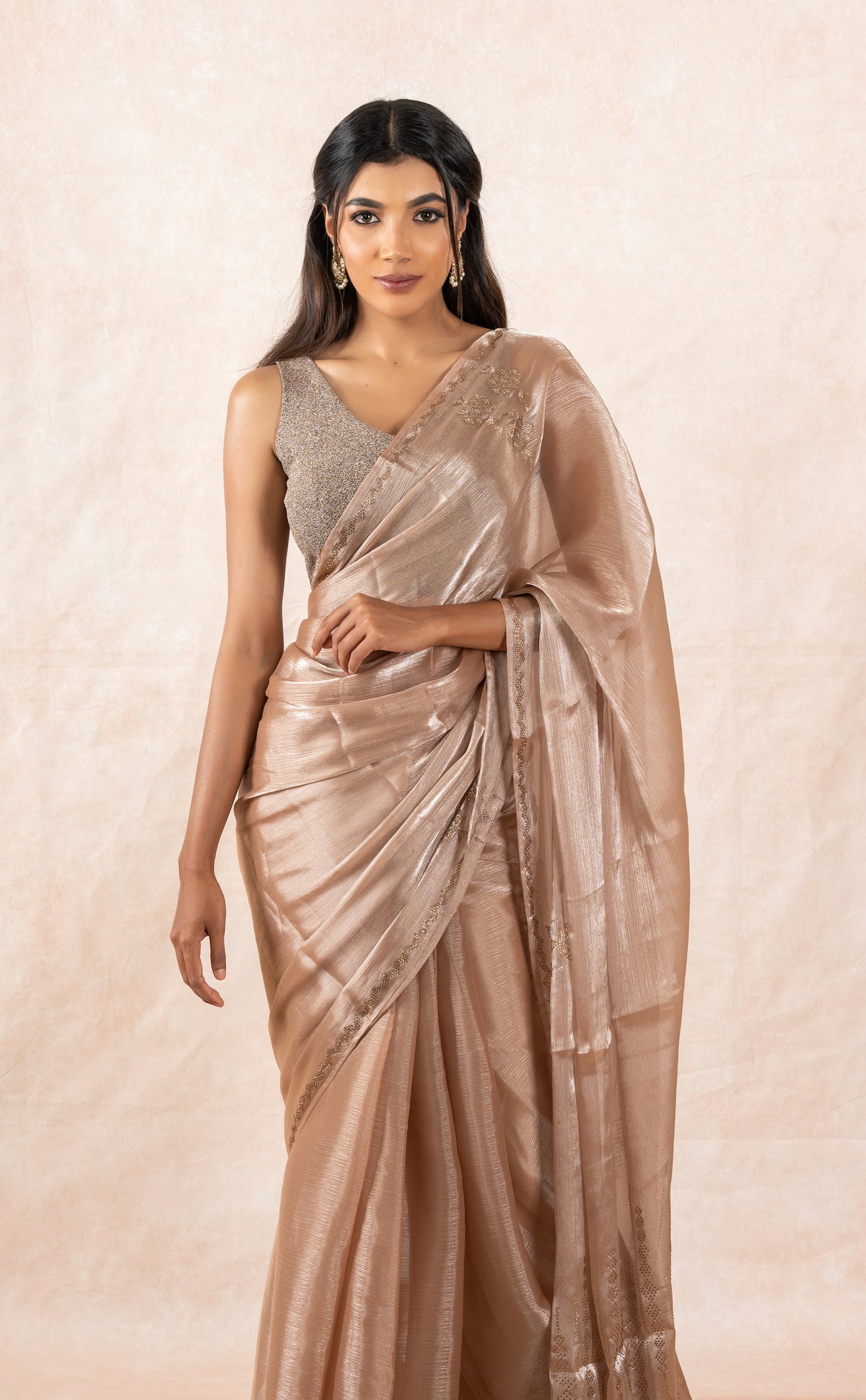 A model of Le Pleat drapede in a sheer rosegold chiffon designer saree with rosegold sleeveless glitter blouse and gold buff saree shaper