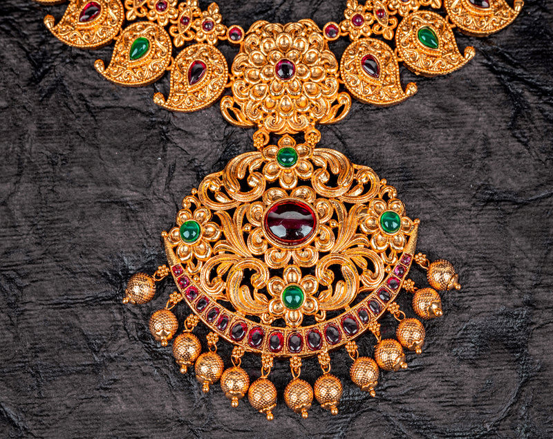 A traditional Indian necklace set in mango design with red and green kemp stone and khumkas