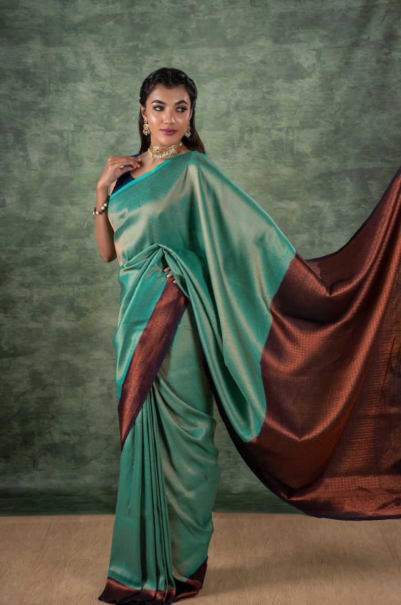 A model of le pleat draped in a lightweight banana's art silk saree with a sleeveless blue raw silk blouse and dark blue saree shaper and Amira necklace set.