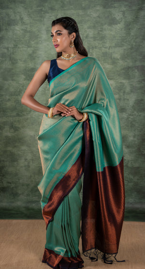 A model of le pleat draped in a lightweight banana's art silk saree with a sleeveless blue raw silk blouse and dark blue saree shaper and Amira necklace set.