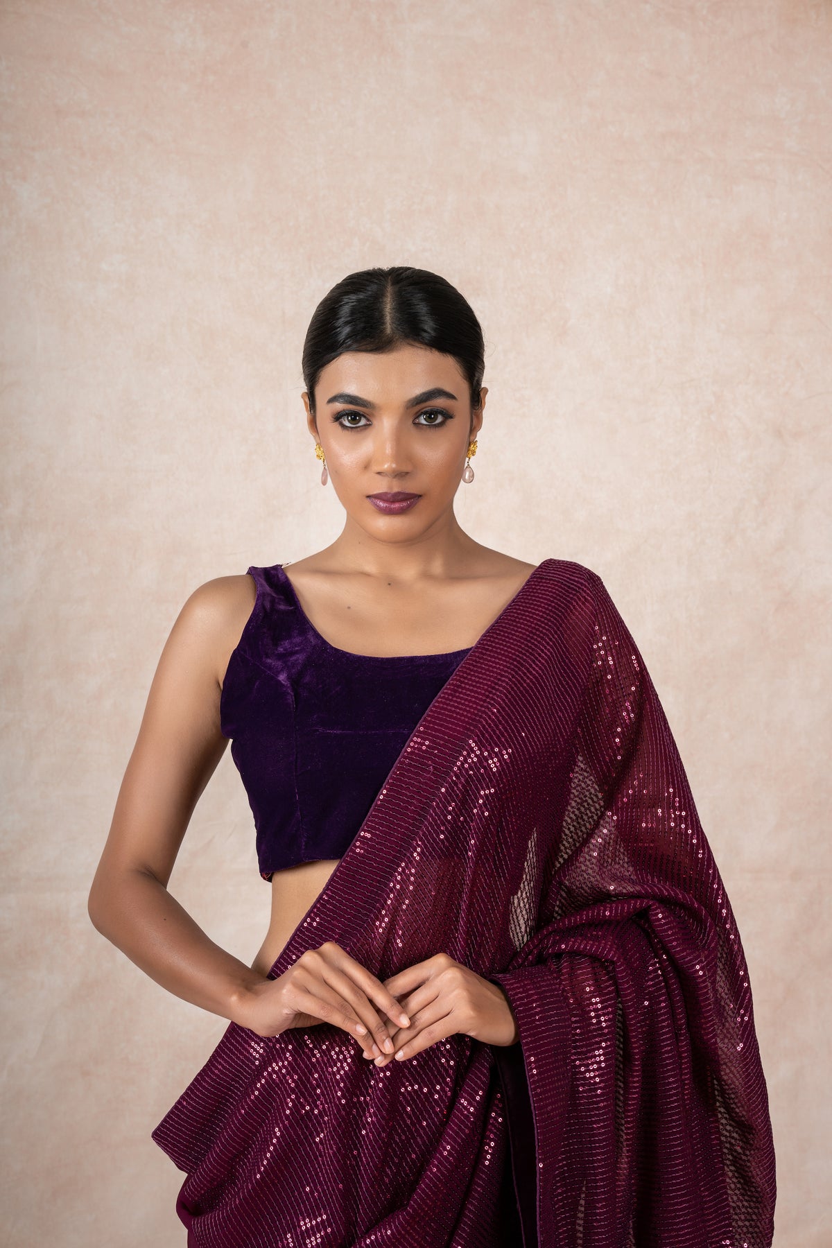 A model of Le Pleat draped in a wine color sequin georgette saree with violet velvet blouse and maroon saree shaper