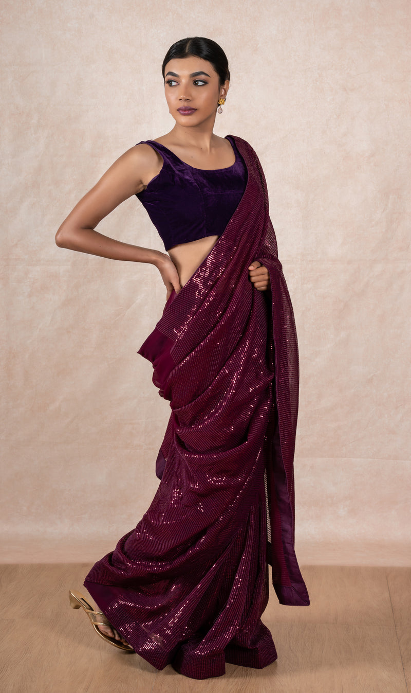 A model of Le Pleat draped in a wine color sequin georgette saree with violet velvet blouse and maroon saree shaper