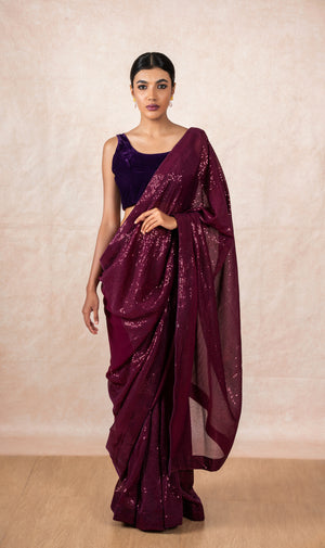 A model of Le Pleat draped in a wine color sequin georgette saree with violet velvet blouse and maroon saree shaper