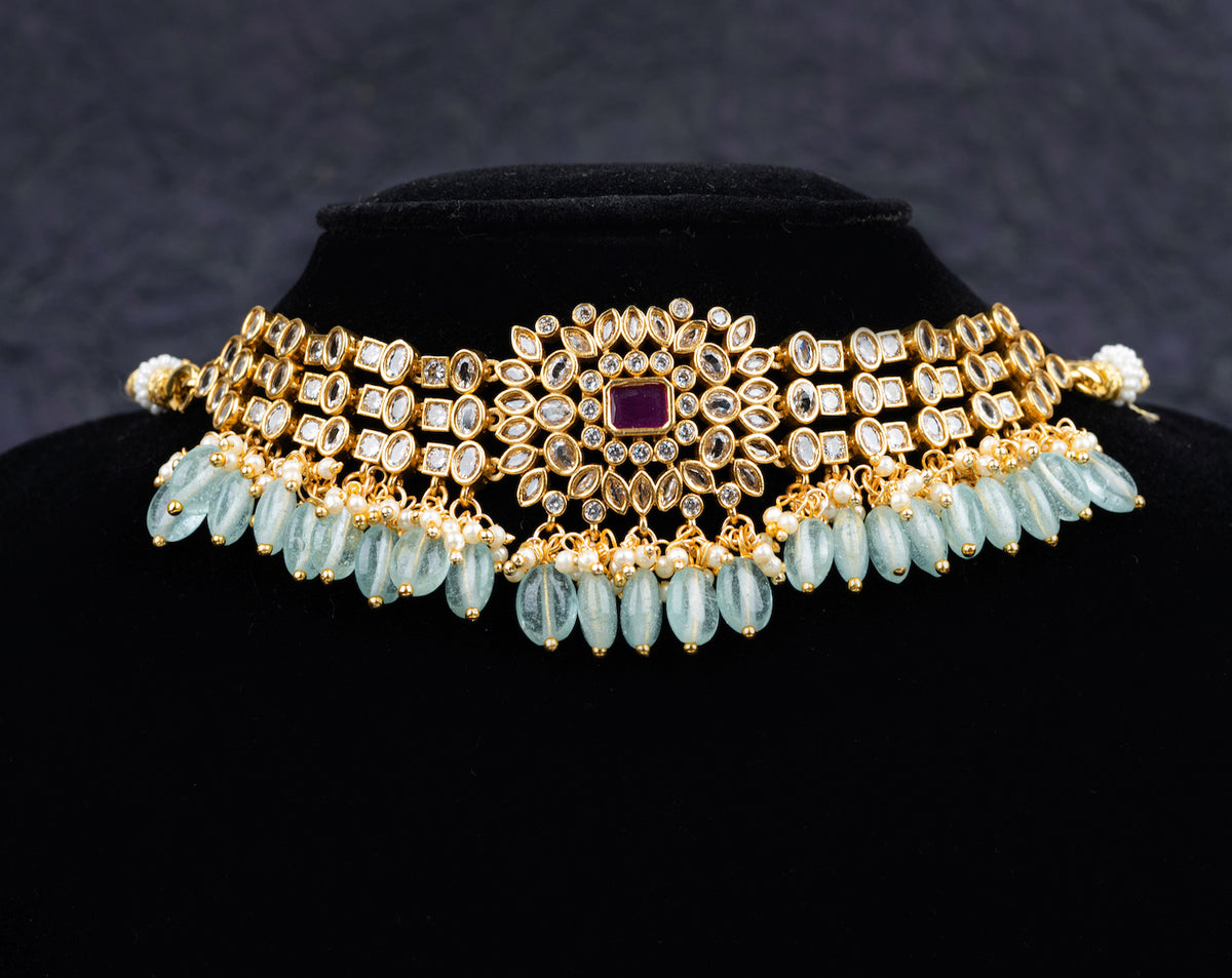 A fancy choker set with earrings desiged with blue beads and white kundan stones